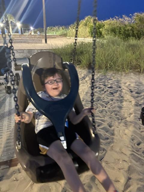 Logan swings in a park in the full-body swing with an over-the-shoulder harness to keep him safely seated.